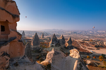 Closeup ancient Goreme cave in big stone, hot air balloons fly over deep canyons, valleys Cappadocia National Park with sunlight, Turkey Travel