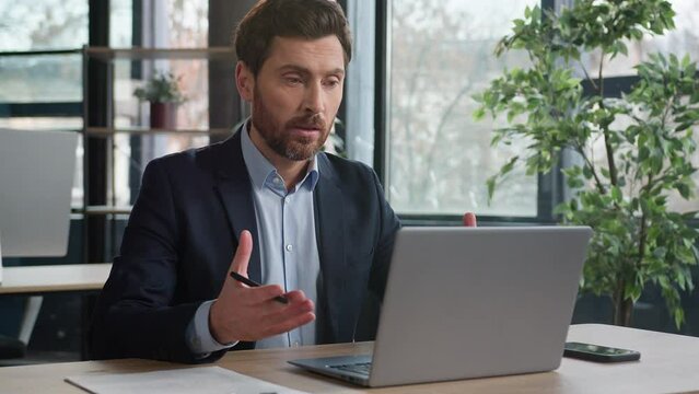 Serious caucasian businessman talking video call laptop in office man entrepreneur leader hr manager conduct remote chat interview at online conference using computer writing notes distance learning