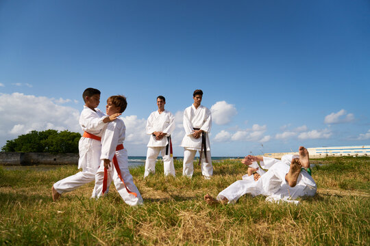 Combat and extreme sports, hispanic men and children exercising in karate and traditional martial arts. Simulation of fight on the beach