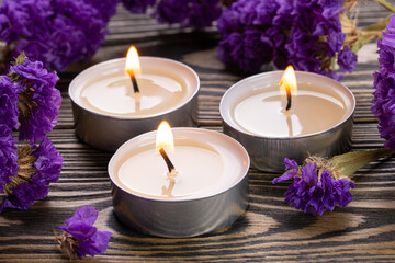 Obraz na płótnie Canvas Candle. Tea Lights Candle. Mini Tealight candles for home decoration. Flowers on wooden table. Dripless and long lasting paraffin or white beeswax. Good for essential oil diffuser or aroma lamps.