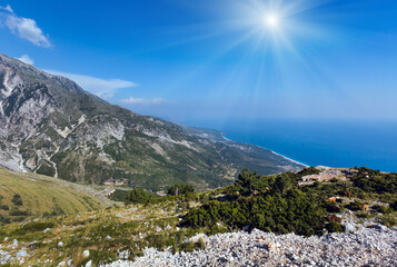Fototapeta na wymiar Summer Llogara pass sunshiny view with road, herd of goats on slope and sea water surface (Albania)