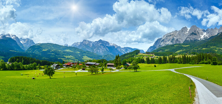Summer sunshiny Alpine mountain country panorama with grassy meadow and road to village (Austria)