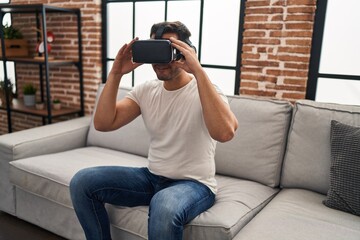 Young hispanic man playing video game using virtual reality glasses at home © Krakenimages.com