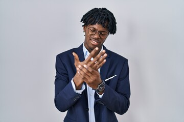 Young african man with dreadlocks wearing business jacket over white background suffering pain on...