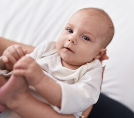 Adorable caucasian baby on mother hands at bedroom