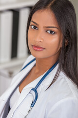 A beautiful Indian Asian female medical doctor in a hospital office happy and smiling with stethoscope