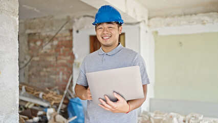  architect using laptop smiling at construction site