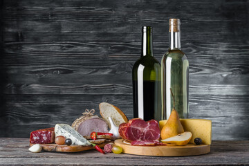 Wine, cheese and meat on a wooden rustic table, food background