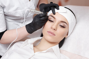 Permanent makeup. Permanent tattooing of eyebrows. Cosmetologist applying permanent make up on...