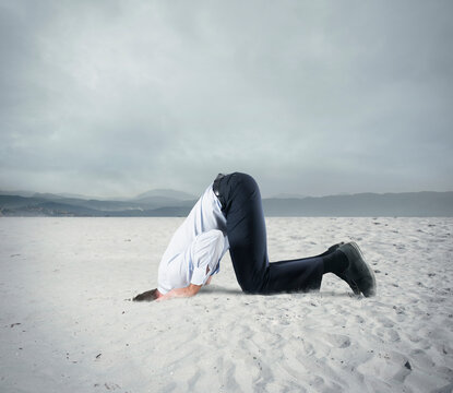 Afraid businessman hide his head under the ground like an ostrich. Fear of crisis concept