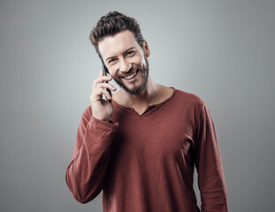 Young smiling cheerful man having a phone call and looking at camera