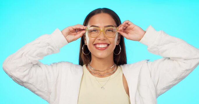 Blue background, stylish and face of a woman with glasses for vision, eyewear and eye care. Happy, trendy and portrait of a young girl with confidence in specs isolated on a studio background