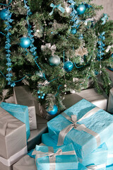Christmas tree decorated with blue and silver Christmas decorations and wrapped gifts
