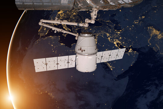 SpaceX Dragon orbiting the planet Earth. Elements of this image furnished by NASA. - Powered by Adobe