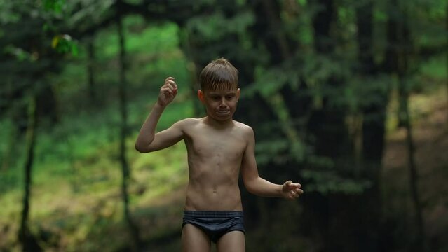 Caucasian boy Mowgli enjoys nature, wet after swimming. Creative. Boy child in swimwear with green jungles on the background.