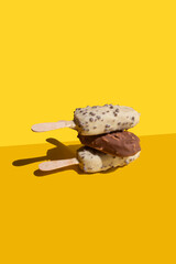 white and milk chocolate, ice cream stick balance on a yellow background