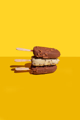 white and milk chocolate, ice cream ( popsicle ) balance on a yellow background