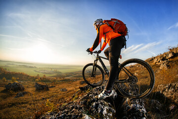 A cyclist with a red backpack on a background of blue sky. Wide angle. Beautiful landscape with...
