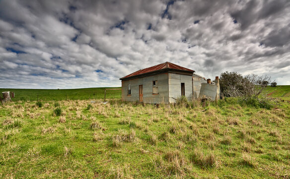 Abandoned farm homstead with corrugated iron roof and walls and boarded up windows left to the elements and now in disrepair