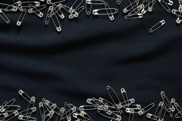 Safety pins on black fabric. Sewing texture background