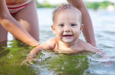 Young woman and little son playing in water on summer day