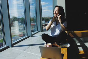 Positive woman with coffee, working video call on laptop with webcams for communication, happy with help woman watching comedy video on netbook in free time sitting in cafe