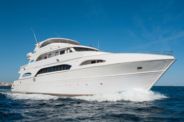 Fototapeta na wymiar A large private motor yacht under way sailing out on tropical sea