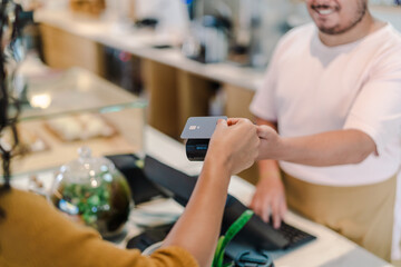 cliente fazendo o pagamento da conta com cartão de crédito por aproximação em uma cafeteria no...