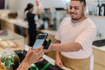 atendente recebendo pagamento por aproximação com o celular em umacafeteria no Brasil
