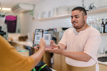 atendente recebendo o pagamento da conta por leitura de código QR em uma cafeteria no Brasil