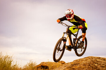 Professional Cyclist Riding the Bike Down Rocky Hill. Extreme Sport Concept. Free Space for Text.