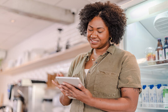 atendente de uma cafeteria no Brasil usando um tablet para anotar o pedido do cliente