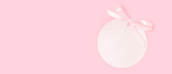 Pink round empty tag with tied ribbon bow. Monochrome composition. Place for text.