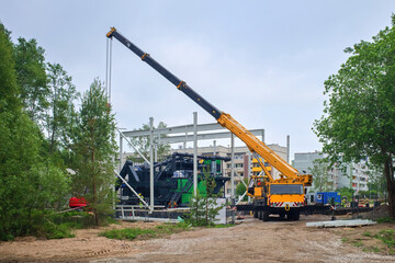 Construction Site. Installation of a boiler room with a biomass boiler. Truck crane on installation.
