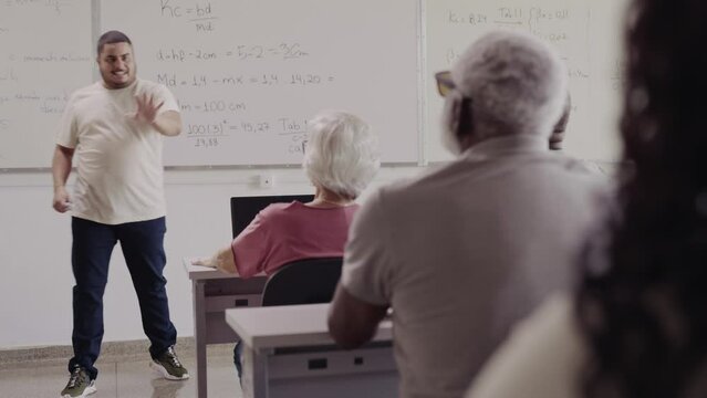 aluno senior Brasileiro de uma turma para adultos levantando a mao para tirr uma duvida durante a aula de matematica em uma escola no Brasil