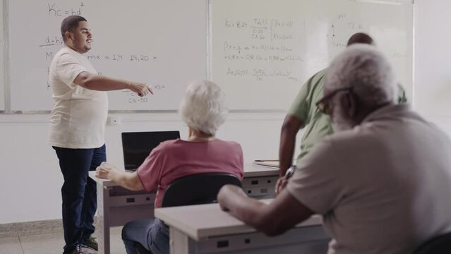 professor Brasileiro chamando um aluno adulto para resolver uma questao de matematica na lousa durante aula em uma faculdade no Brasil