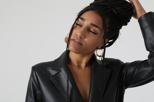 Close-up of African American young woman with long braids, posing at studio. 