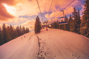Winter mountains panorama with ski slopes and ski lifts in a cloudy day. Sunset soft light with...