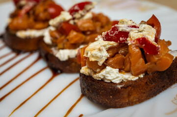 Close up of delicious canapés seasoned with cheese and smoked salmon and spices on a light plate