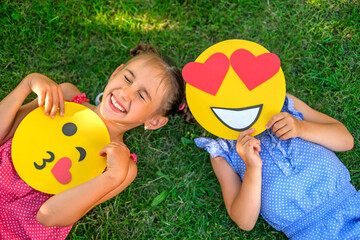 Top view of children with various loving cardboard emoticons in their hands on World Emoji Day. A...