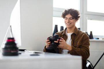Modern arts and creative career concept. Happy smiling photographer man holding camera using computer