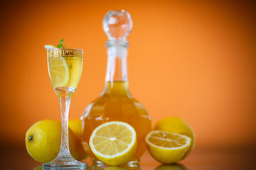 sweet lemon alcoholic brandy in the decanter on an orange background