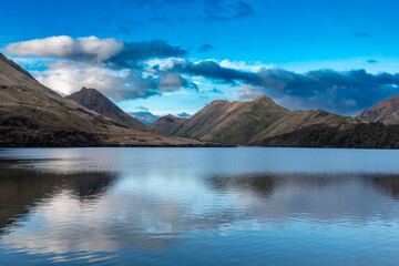 Photograph of Lake Moke with mountains reflecting in the water on a cloudy day outside Queenstown on the South Island of New Zealand