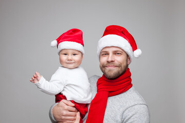 Father with his baby boy wearing Santa hats celebrating Christmas