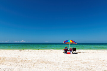 Fototapeta na wymiar Sunny beach with colorful umbrella and beach chairs in tropical beach