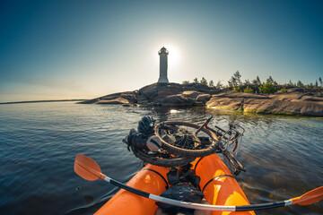A man with a bicycle in a boat near the sea lighthouse
