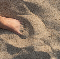 Male foot in the sand on the beach. Barefoot on the beach. Footprints in the sand.