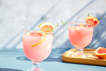 Chilled cocktails with fresh grapefruit juice, served with a sprig of thyme and fresh fruit slices. Refreshing summer cocktails with citrus fruits.