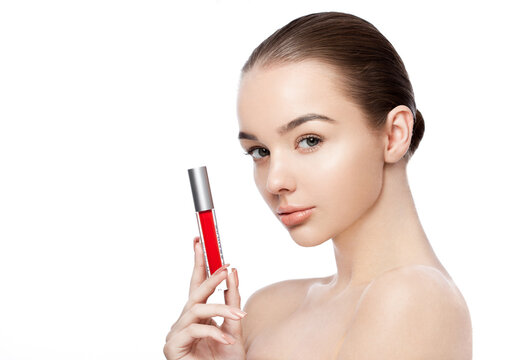 Beautiful girl holding liquid red lipstick container on white background