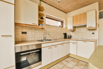a small kitchen with white cabinets and wood paneled ceiling above the sink is an oven, dishwasher...